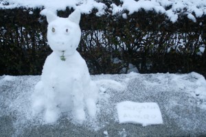 This snow cat watched the visitors pass by its bench.